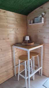 a table and two stools in a room with wooden walls at Un aparté bohême "La Roubane" in Puyravault +18 photos