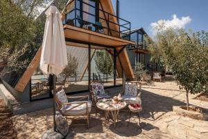 a patio with a table and an umbrella and chairs at Maison Jwar - Luxury A-Shape Cabins - A Unique Summer Getaway in Ḩārat at Taḩtā
