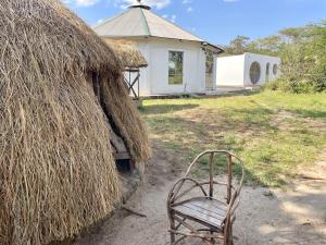 a chair sitting in front of a hut at Akamba Traditional Grass Hut in Emali