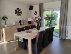 a dining room table with purple chairs and a vase of flowers at Maison Belle Vue Ronse in Ronse