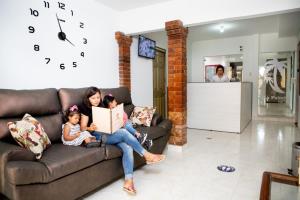 a woman and two children sitting on a couch with a clock at Hotel La Palmita in Pacho