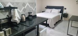 a bedroom with a bed and a kitchen with a sink at Pousada Rainha da Serra in Espirito Santo Do Pinhal