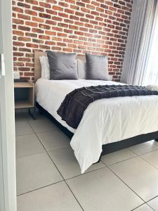 a bed in a room with a brick wall at 166 Green valley in Boschrand