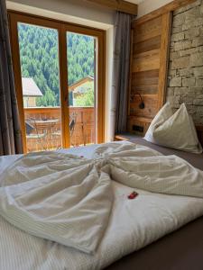 a large bed in a room with a large window at Garni Appartements Des Alpes in Solda