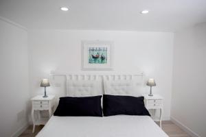 a white bedroom with a white bed and two night stands at Residence Ventimiglia in Gangi