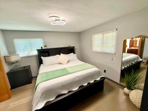 a bedroom with a large bed and two windows at Delightful 3 Bd Home with King size bed, hot tub, playground! in Indianapolis