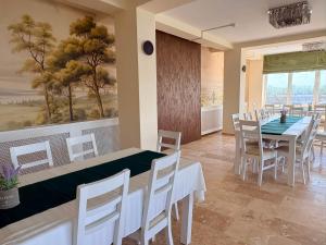a dining room with white tables and chairs and a painting at Hotel Sucidava in Corabia
