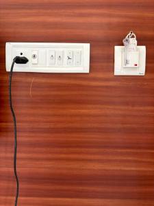 a electrical outlet on a wooden wall with a cord at La Couronne Seaview Resort in Pondicherry