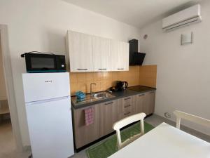 a small kitchen with a white refrigerator and a microwave at Ginestra in Galtellì