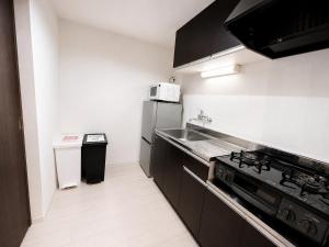 a kitchen with a sink and a stainless steel refrigerator at Excel 琴似 -FIX HOME- in Sapporo