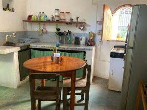 a kitchen with a wooden table with chairs and a refrigerator at Casa Ozomalli in San Pedro Pochutla