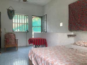 a bedroom with a bed and a chair and windows at Casa Ozomalli in San Pedro Pochutla