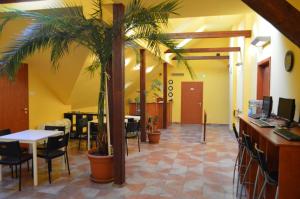 a lobby with tables and chairs and a palm tree at Bordany Hostel in Bordány