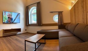 a living room with a couch and a tv at Marktplatz Apartments Lofer in Lofer