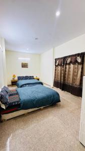 a bedroom with a large bed with a blue comforter at CLOUD HEIGHTS COTTAGE NATHIA GALi in Nathia Gali