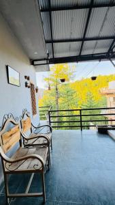 two chairs sitting on a balcony with a view of trees at CLOUD HEIGHTS COTTAGE NATHIA GALi in Nathia Gali
