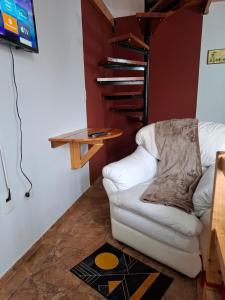 a living room with a white chair and a tv at Brisas Andinas in Malargüe