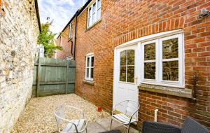 a brick building with two chairs and a white door at 2 Crown Barton in Glastonbury