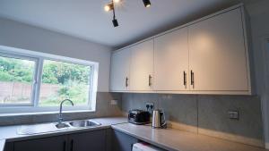 a kitchen with white cabinets and a sink and a window at Whitebeam in Solihull