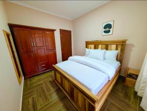 a bedroom with a large bed with white sheets at Kijani Pazuri Cottages in Lushoto