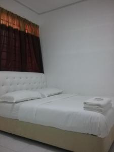 a bedroom with a white bed with a window at Anjung Homestay in Sepang