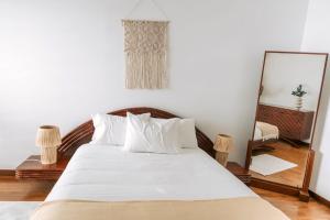 a bedroom with a bed with white sheets and a mirror at Casa do Suave Mar in Esposende +29 photos