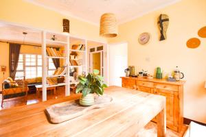 a kitchen with a wooden table and a living room at Utamaduni House B&B in Arusha