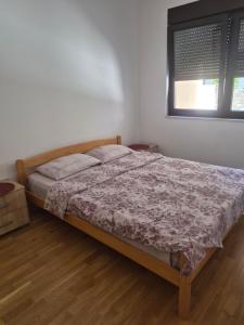 a bedroom with a bed in a room with a window at M&M Apartman 2 in Rafailovici