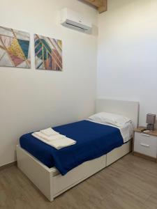 a bedroom with a bed with a blue blanket and two paintings at Copernico casa vacanze, nel centro di Lecce in Lecce