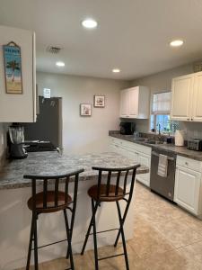 a kitchen with two bar stools and a counter at Seras Home At Vero Beach in Vero Beach +11 photos