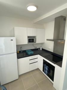 a kitchen with white cabinets and a white refrigerator at Blue sunset - Appartement avec vue mer in Papeete