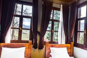 a bedroom with two beds and windows with curtains at Şamlıoğlu Historical Villa in Trabzon