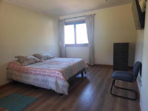 a bedroom with a bed and a window and a chair at Apart bio bio in Concepción