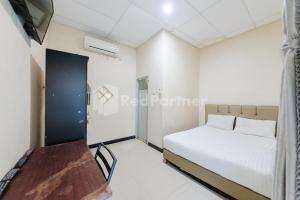 a bedroom with a bed and a table in a room at Wisma Merdeka Syariah RedPartner in Palembang