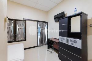 a living room with a tv and a desk at Wisma Merdeka Syariah RedPartner in Palembang +20 photos