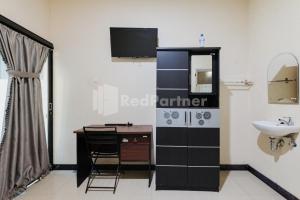 a bathroom with a sink and a desk and a mirror at Wisma Merdeka Syariah RedPartner in Palembang