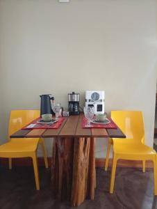 a wooden table with two yellow chairs and a microwave at Hospedaria Portal das Montanhas in Ibicoara +10 photos