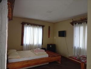 a small bedroom with a bed and two windows at Hospedaria Portal das Montanhas in Ibicoara