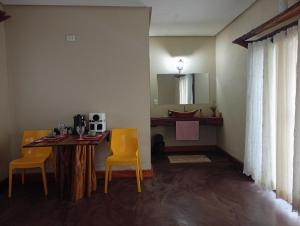 a dining room with a table and two yellow chairs at Hospedaria Portal das Montanhas in Ibicoara