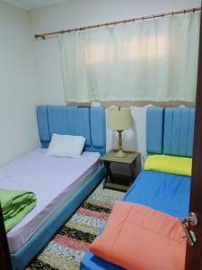 a room with two beds and a table with a lamp at بورتوجولف portogolf in El Alamein