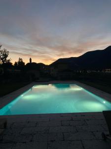 a large swimming pool with a sunset in the background at franciacorta iseo lake house in Clusane sul Lago