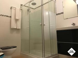 a glass shower in a bathroom with a toilet at Hostal Five Gates in Osuna