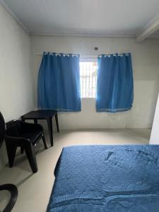 a bedroom with blue curtains and a bed and a window at Hostel Coimbra Araçagi in Macajatuba
