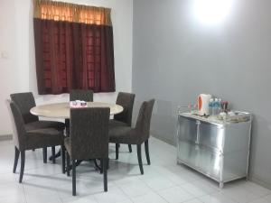 a dining room with a table and chairs and a window at Anjung Homestay in Sepang