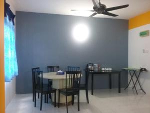 a dining room with a table and chairs and a ceiling fan at Anjung Homestay in Sepang