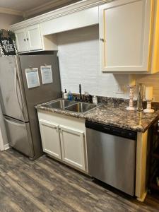 a kitchen with a sink and a stainless steel refrigerator at Lucky 13 Condo in Starkville