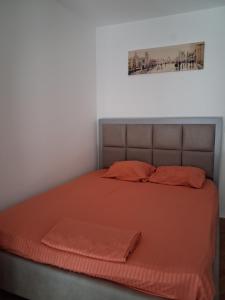 ein Bett mit einer orangefarbenen Bettdecke und zwei orangefarbenen Kissen in der Unterkunft Radoš in Igalo