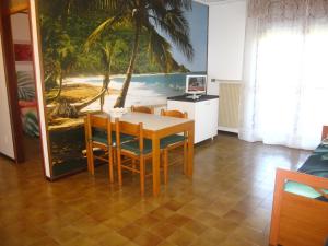 a dining room with a table and a painting of a beach at Appartamento Brubelpi in Lido