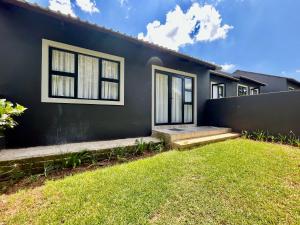 a house with a black wall and a yard at Number 12, Jadde apartments in Sandton