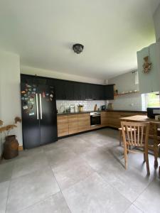 a kitchen with a black refrigerator and a table at Folwark Mazurskie Legendy - Azyl dla Dorosłych in Kruklanki